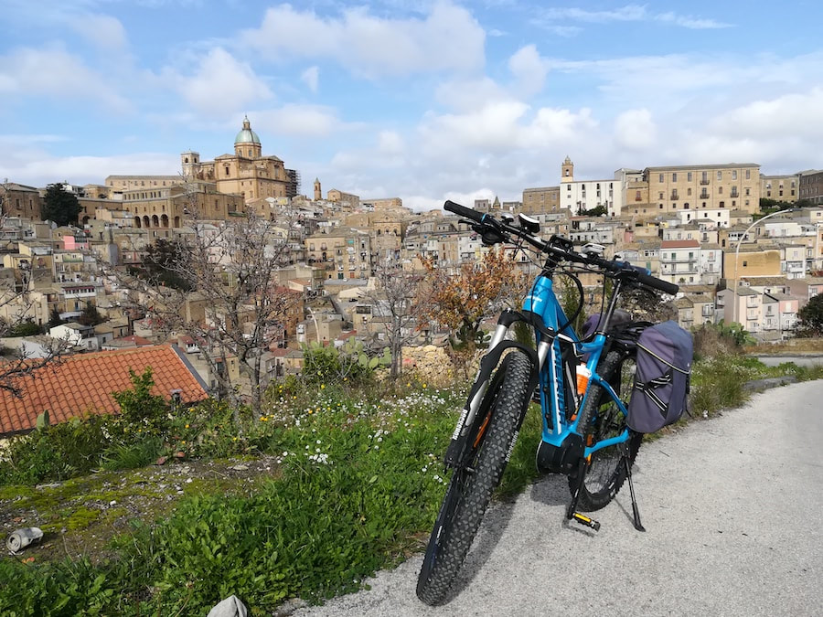Piazza Armerina and its cathedral seen from a panoramic road, with a rental bike in the foreground